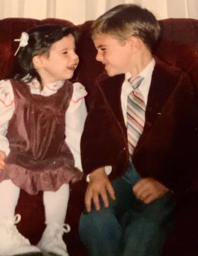 Kelly O'Brien and her brother as young children smiling at each other.