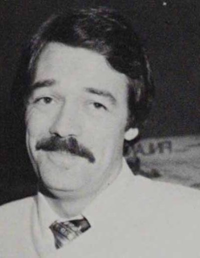 A black and white closeup photo of a young Bob Foley smiling at the camera in the 1980s.